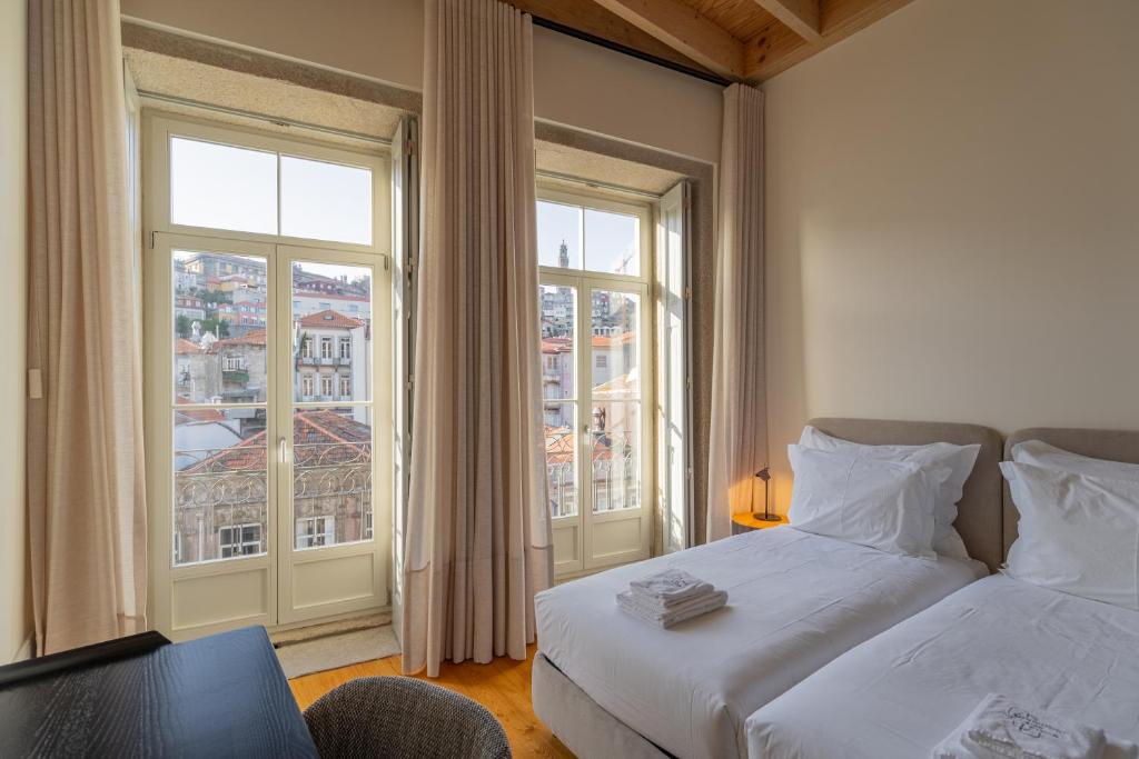 a bedroom with two beds and a table and windows at Mouzinho Village River in Porto