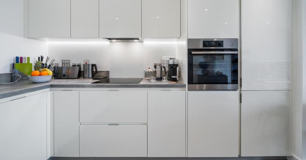 - une cuisine blanche avec des armoires et des appareils blancs dans l'établissement Impeccable Flat Near Canary Wharf and the City, à Londres
