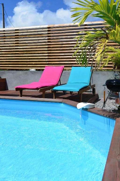 duas cadeiras sentadas ao lado de uma piscina em Maison Piscine personnelle vue mer COSY em Le Marin