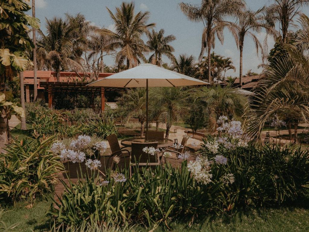 a patio with an umbrella and chairs and flowers at Pousada Recanto da Grande Paz in Alto Paraíso de Goiás