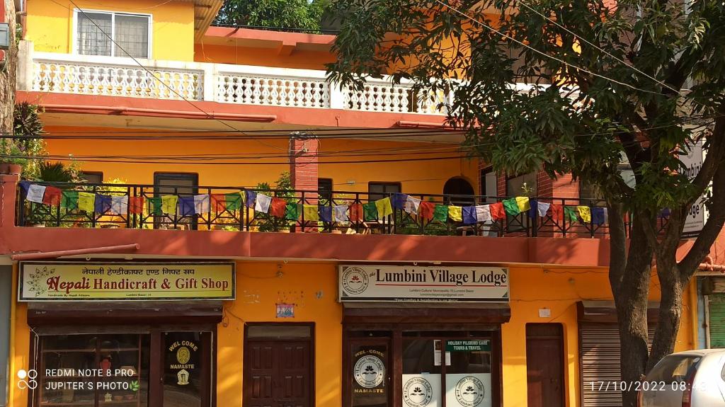 a yellow building with a balcony with chairs on it at The Lumbini Village Lodge in Lumbini