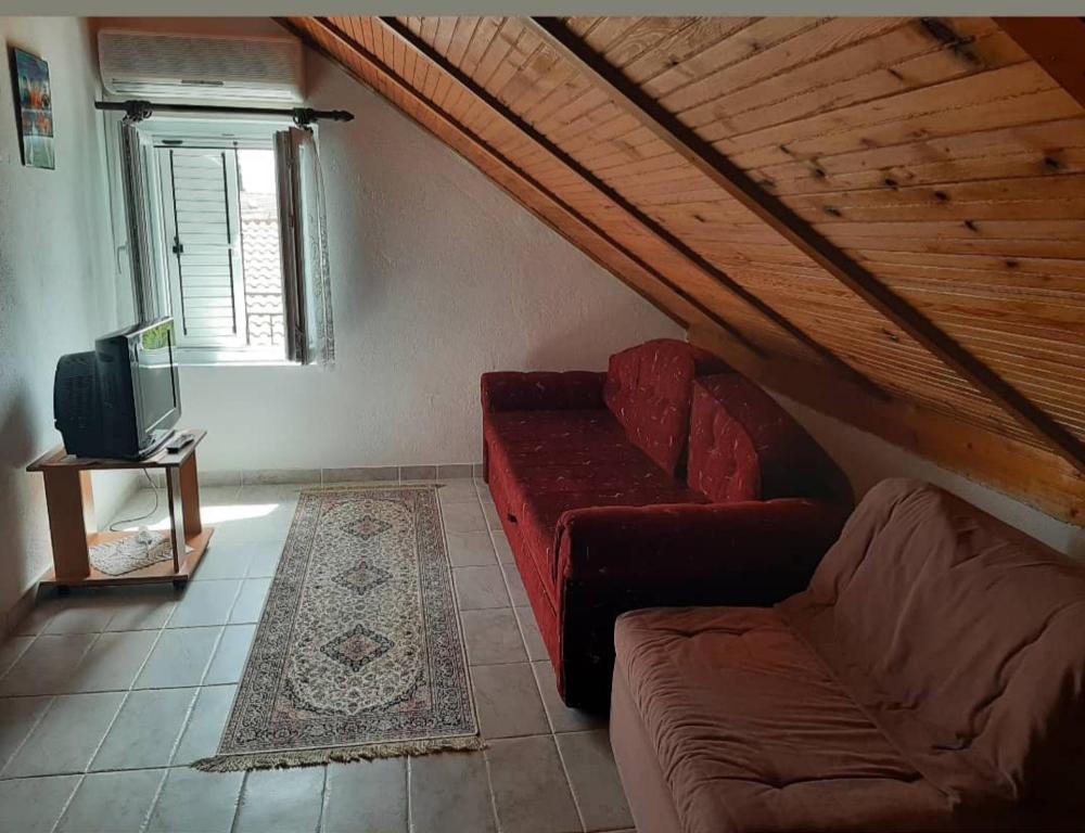 uma sala de estar com um sofá vermelho e uma televisão em Apartman Marija em Tivat