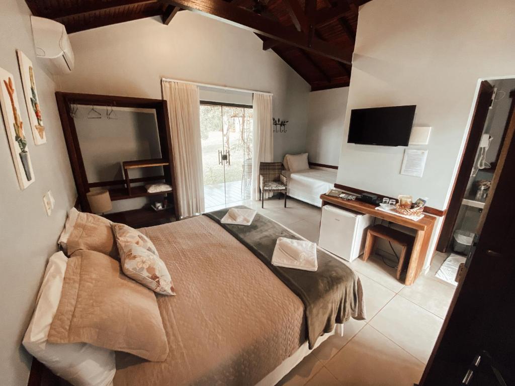 a bedroom with a large bed and a living room at Pousada Recanto da Grande Paz in Alto Paraíso de Goiás