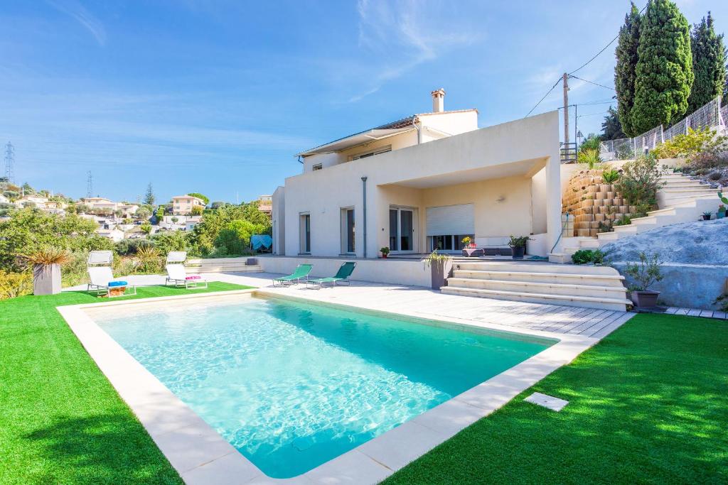 eine Villa mit einem Pool vor einem Haus in der Unterkunft BELLET HILLS VI4193 by Riviera Holiday Homes in Nizza