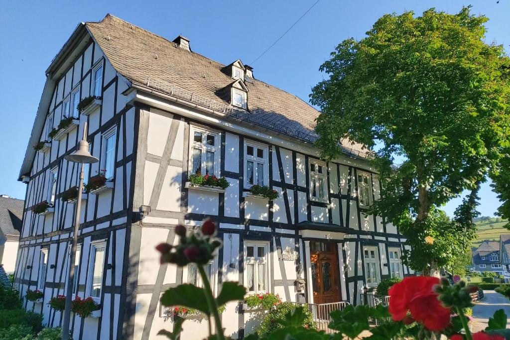 a black and white building with flowers in front of it at Landhotel Albers in Schmallenberg