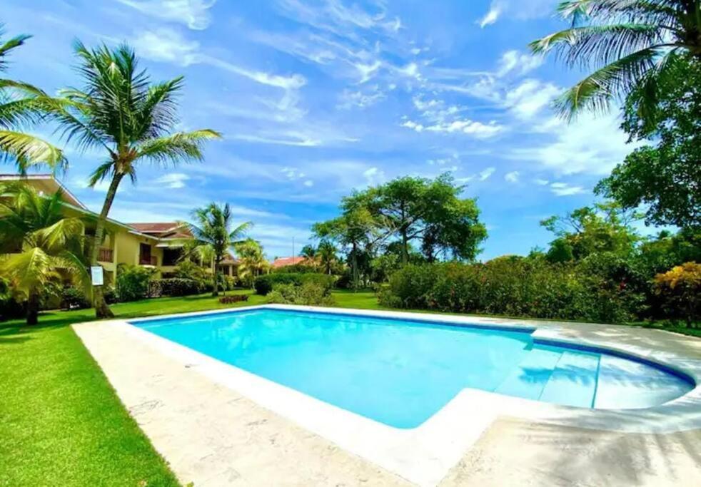 a swimming pool in a backyard with a lawn and palm trees at Luxury apto 3 rooms+pool+ campo de golf. Cocotal in Punta Cana