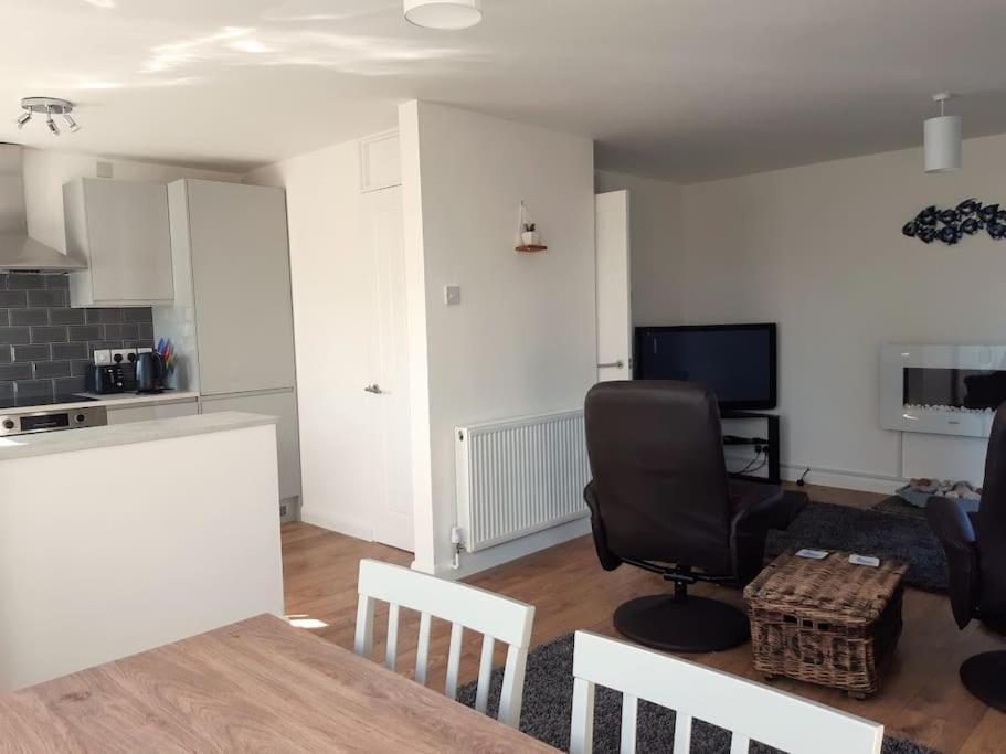 a living room with a table and a chair at The Getaway - Modern 2 Bedroom Brixham Bungalow with sea peeps in Brixham