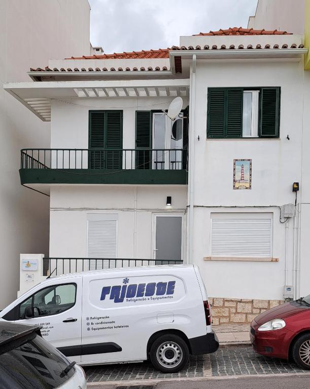 a white van parked in front of a white house at Casa Faroleiro in Nazaré