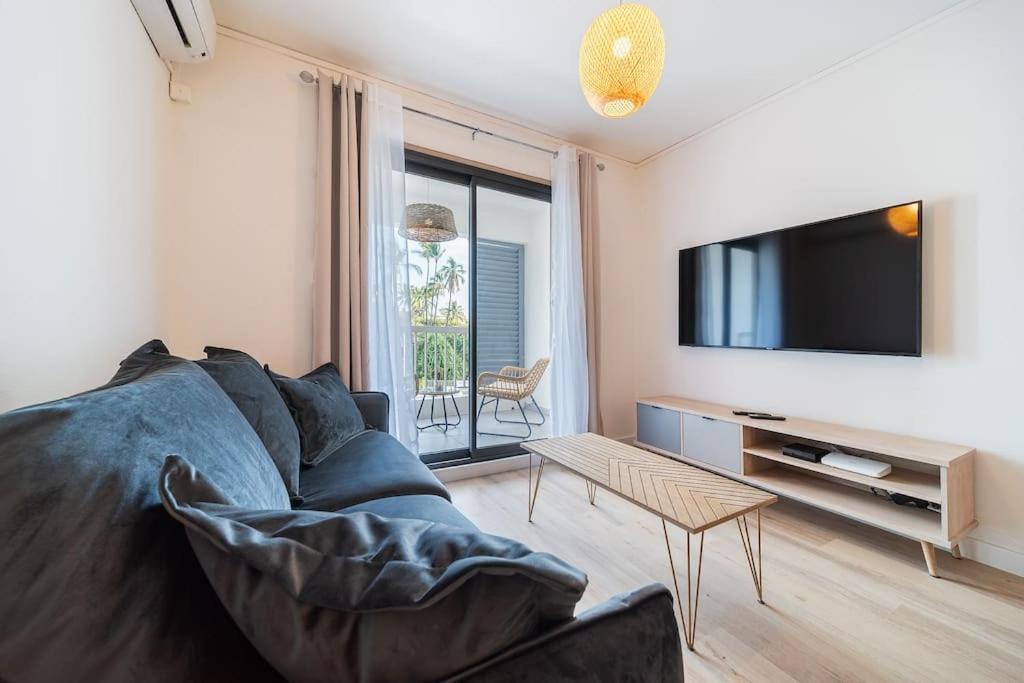 uma sala de estar com um sofá e uma televisão de ecrã plano em Studio Les Aigrettes em Saint-Gilles-les-Bains