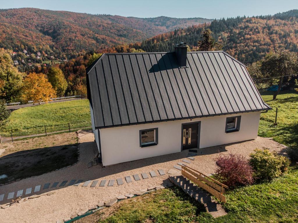 uma pequena casa branca com um banco num campo em Beskidzka Oaza em Targanice