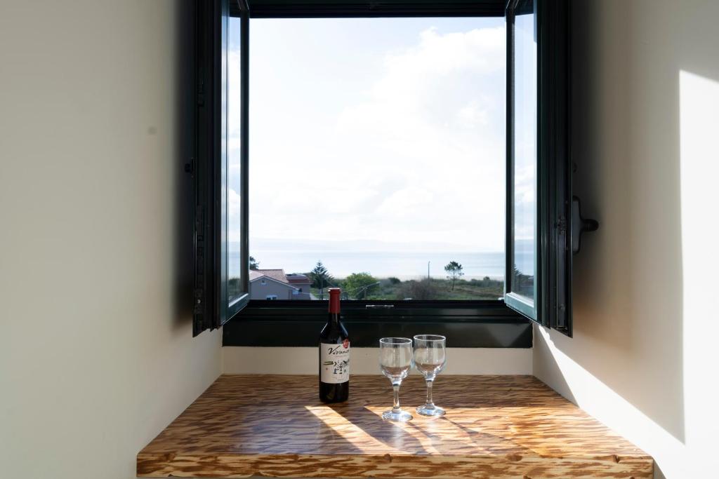 twee glazen wijn zittend op een tafel voor een raam bij Apartamento Cabra Playa de Langosteira en Finisterre con vistas al mar in San Martín de Arriba