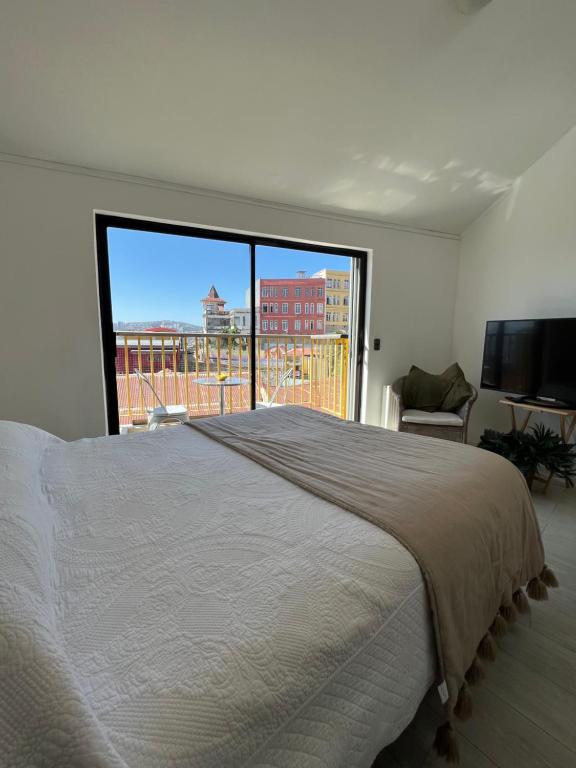 een slaapkamer met een groot bed en een groot raam bij Hermoso departamento en cerro Bellavista in Valparaíso