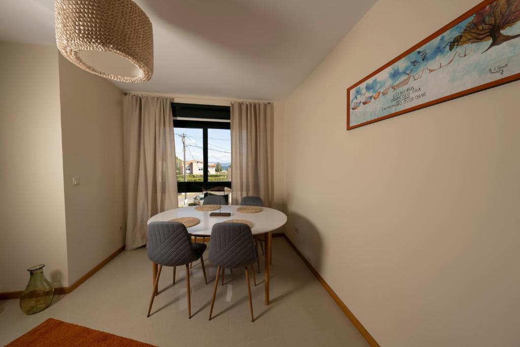 uma sala de jantar com uma mesa e cadeiras e uma janela em Apartamento Pinto Playa de Langosteira en Finisterre con vistas al mar em San Martín de Arriba