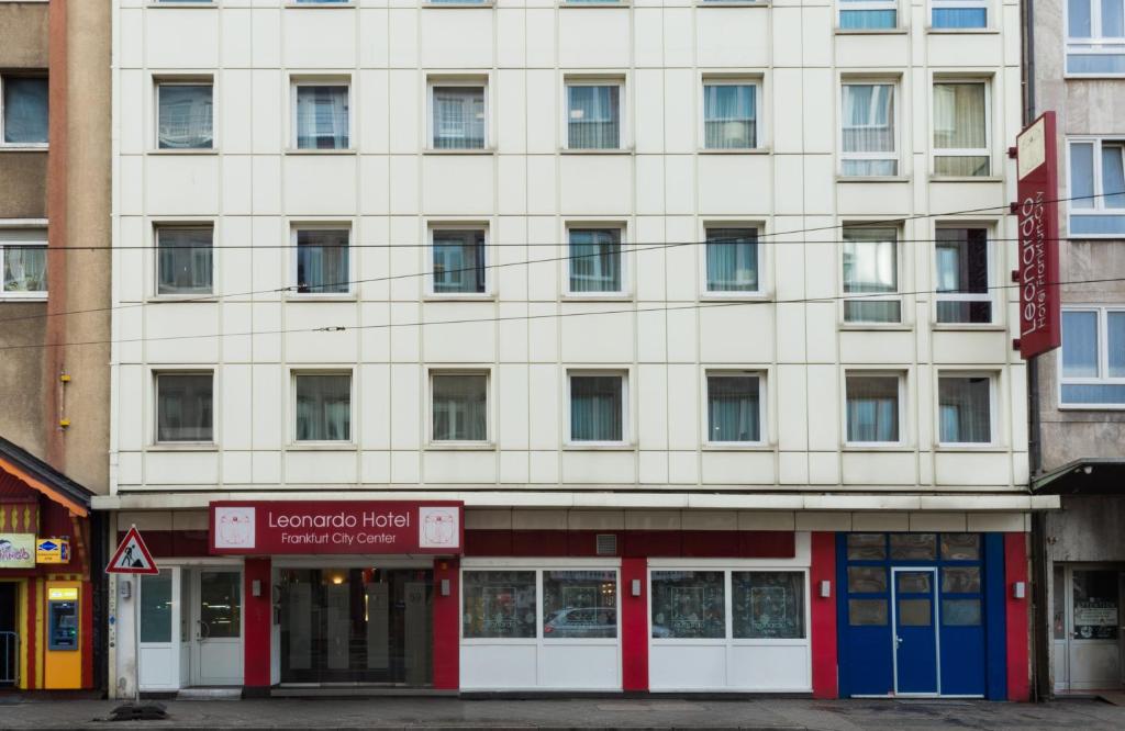a large white building with red and blue doors at Leonardo Hotel Frankfurt City Center in Frankfurt