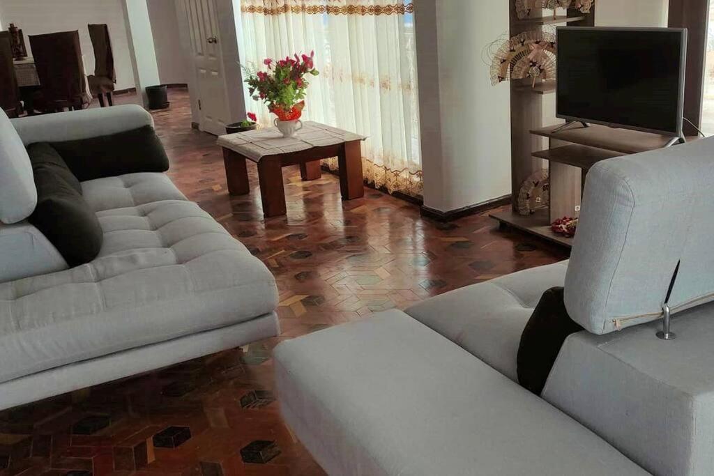 uma sala de estar com um sofá e uma televisão em Hermoso Departamento Central Familiar Tu Refugio con Impresionantes Vistas a la Ciudad, Montañas y Nevados em Riobamba