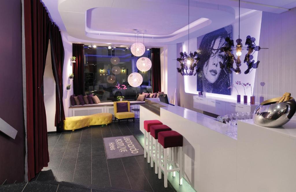 um quarto com um bar com cadeiras vermelhas e uma sala de estar em Leonardo Boutique Hotel Munich em Munique