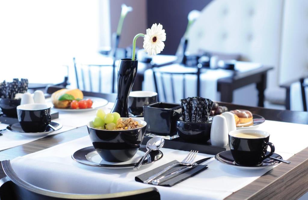 a table with plates of food and cups of coffee at Leonardo Boutique Hotel Munich in Munich