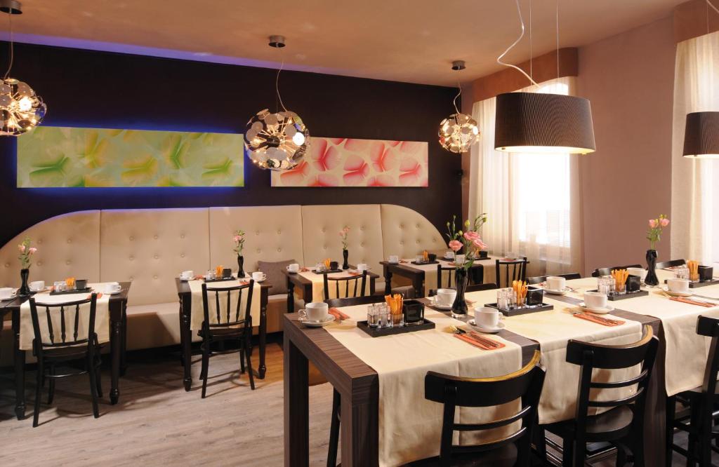 a dining room with tables and chairs and chandeliers at Leonardo Boutique Hotel Munich in Munich