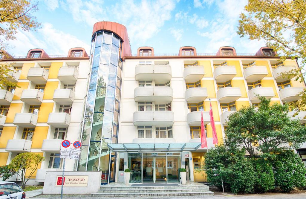 een groot gebouw met geel en wit bij Leonardo Hotel & Residenz München in München