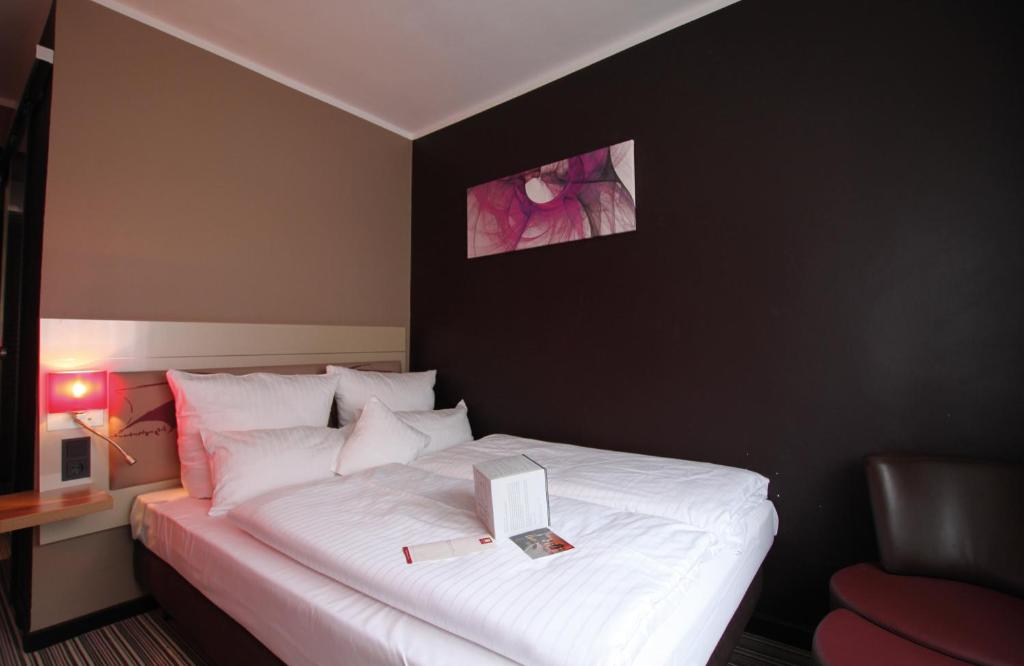 a bedroom with a white bed with a book on it at Leonardo Boutique Hotel Munich in Munich