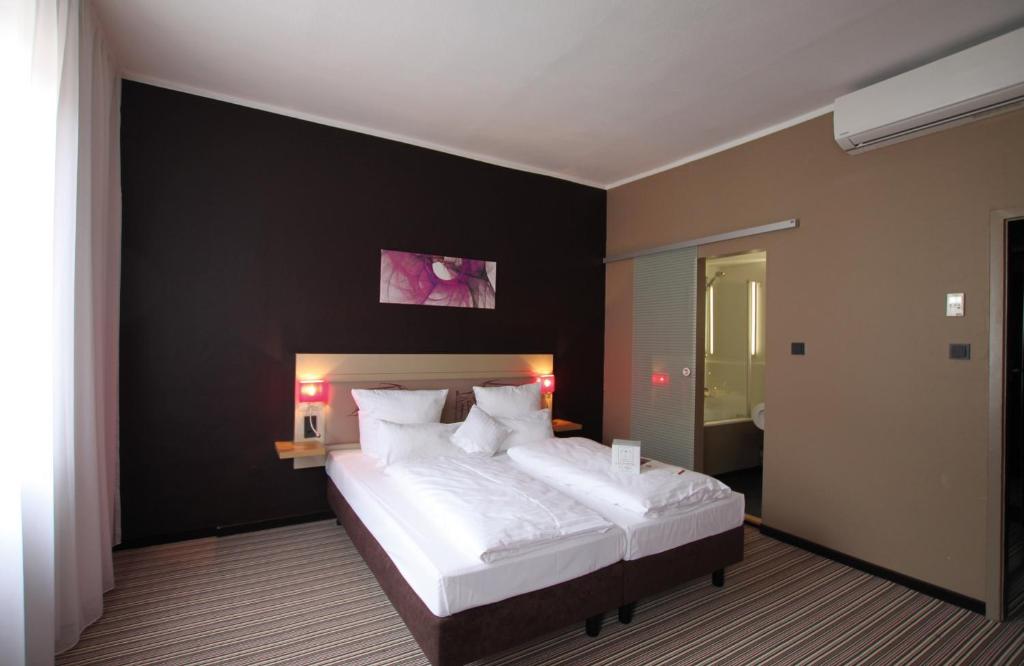 a bedroom with a large bed with a black wall at Leonardo Boutique Hotel Munich in Munich