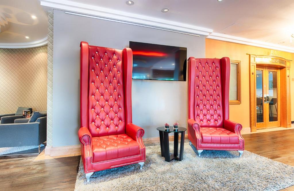 two red chairs sitting in a room at Leonardo Hotel Heidelberg in Heidelberg