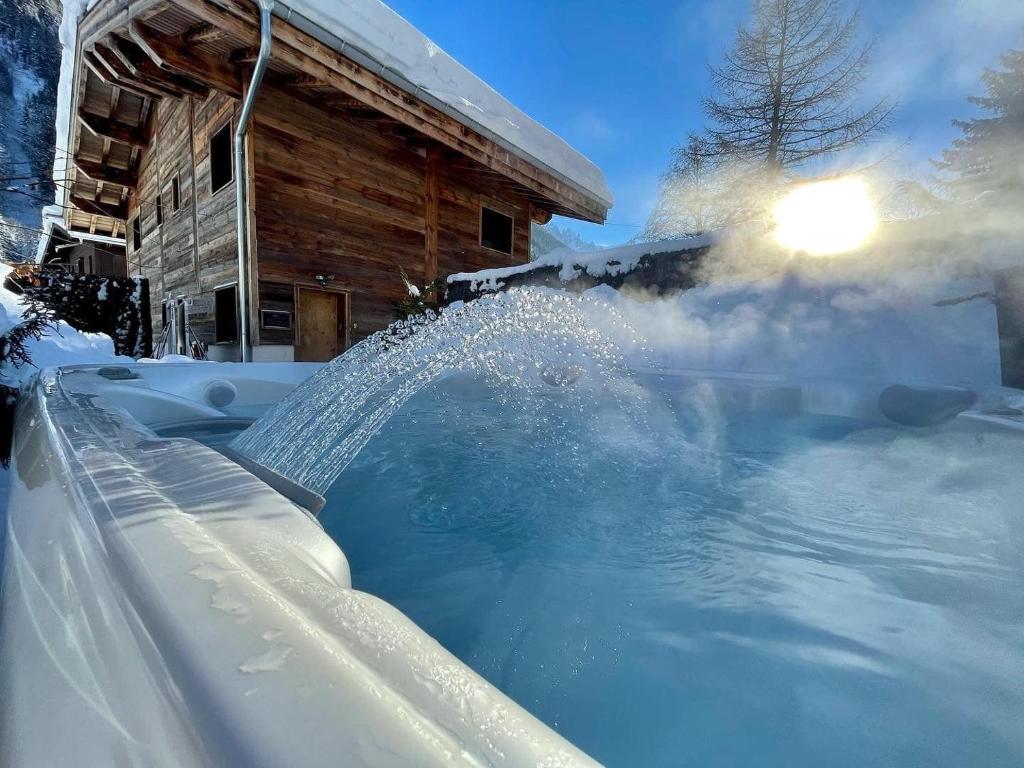 Chalet le petit Nicolas, jacuzzi, vue Mont Blanc في شامونيه مون بلان: حوض استحمام ساخن مغطى بالثلج بجوار كابينة