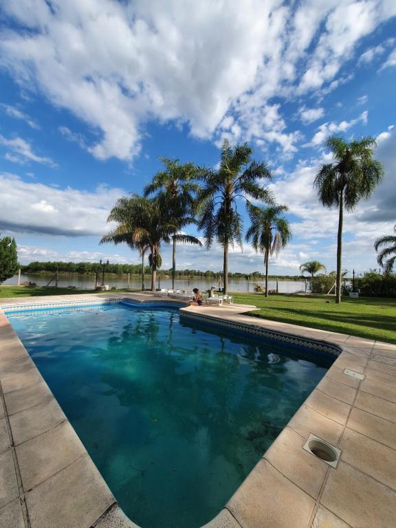 a swimming pool with palm trees in the background at (12 pers. o +) Casa quinta con pileta sobre el río PRECIO DOLAR BILLETE in Santa Fe