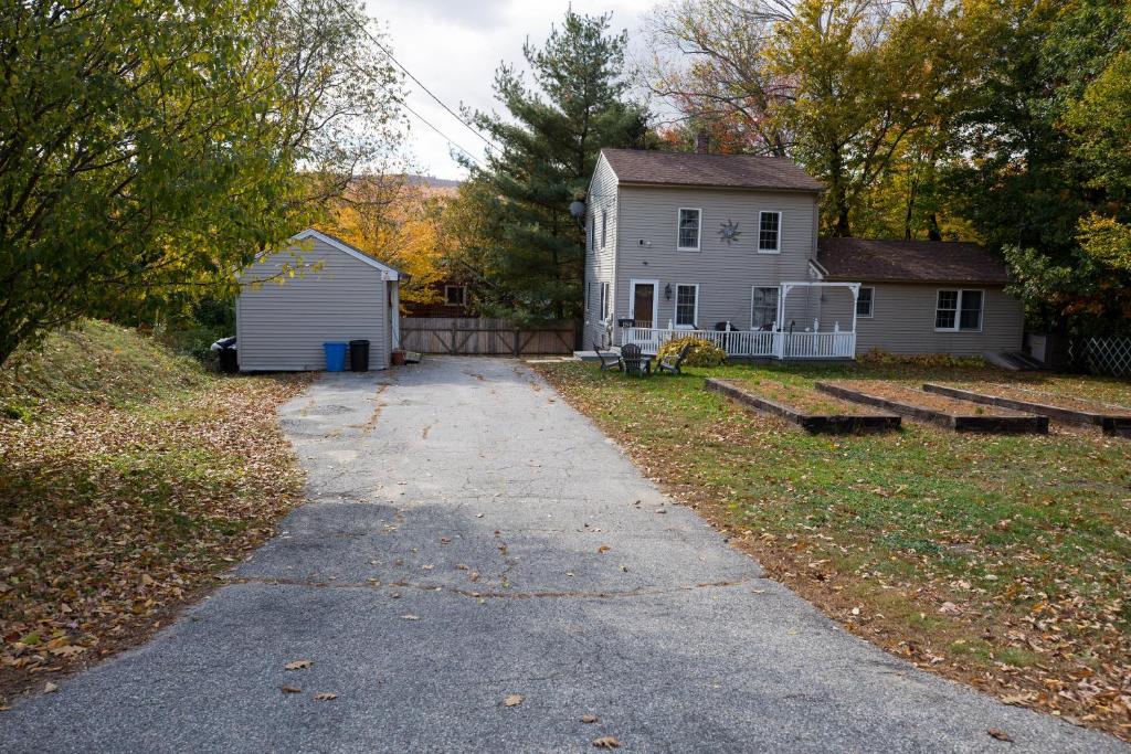 a driveway leading to a white house and a yard at Sunnyside home near Sunday River, Black Mountain, Lakes and Hikes in Rumford