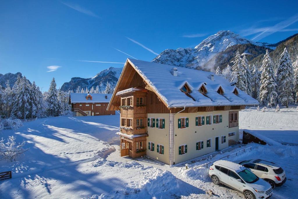 a house with two cars parked in the snow at Natura Boutique Chalet Wellness SPA in Dobbiaco