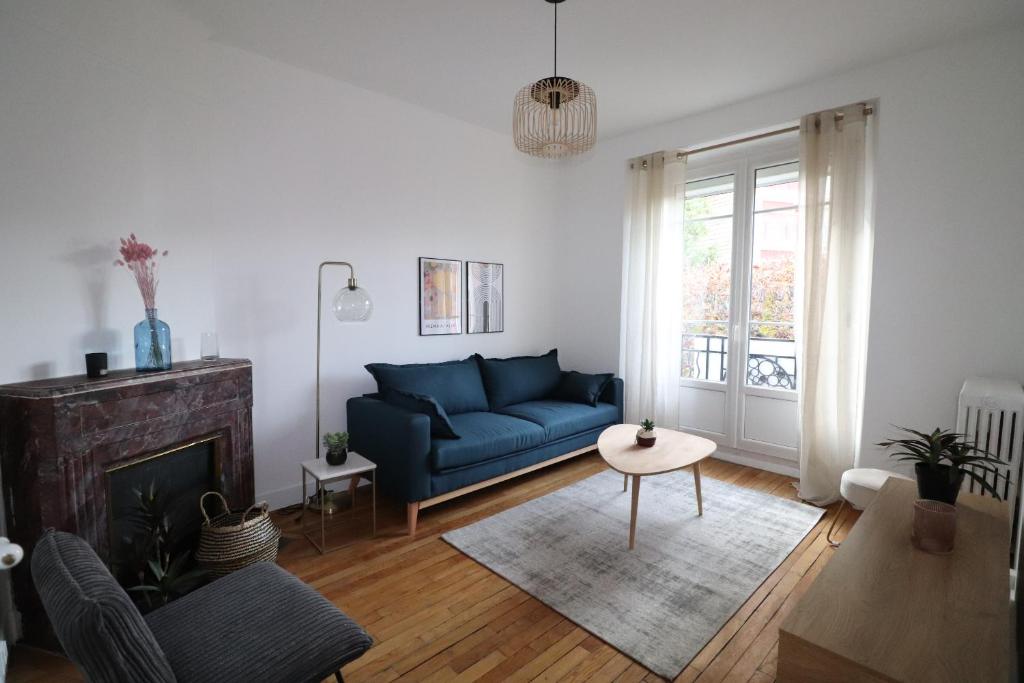 a living room with a blue couch and a fireplace at Superbe Appartement de 45m² à Antony in Antony