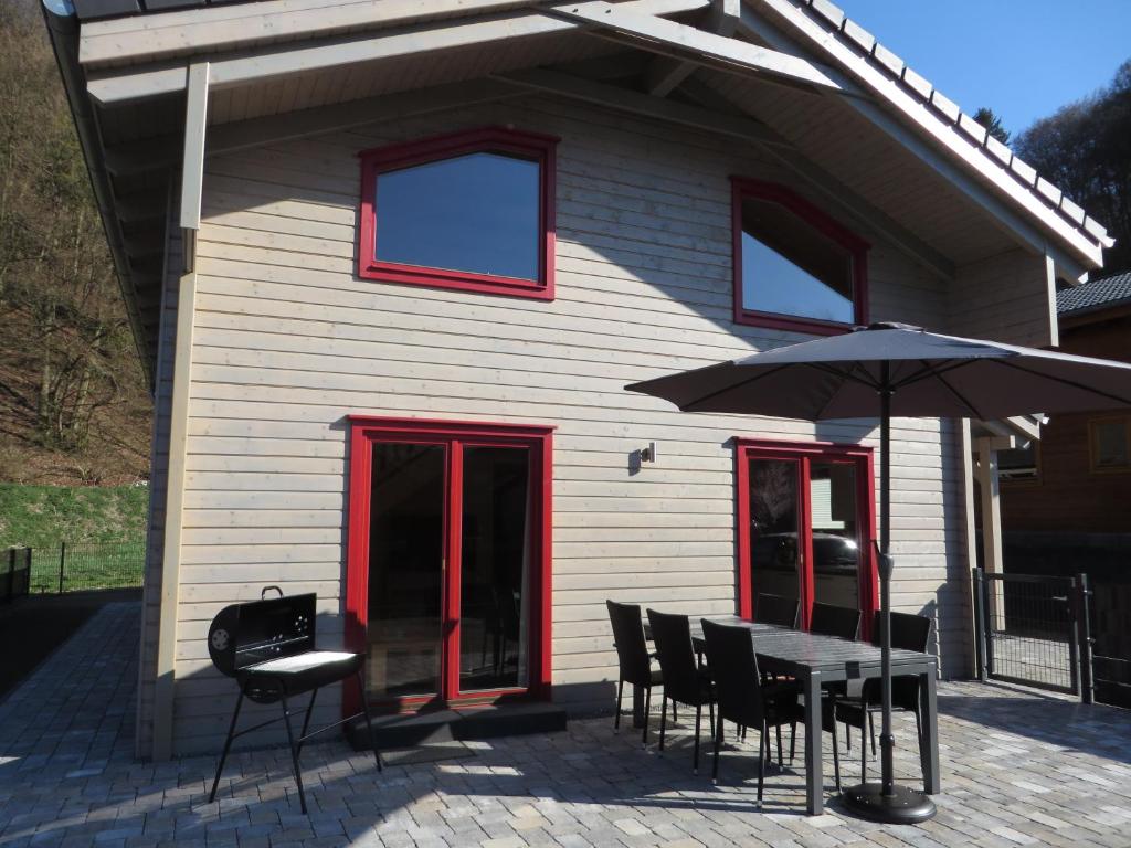 a house with a table and chairs and an umbrella at EifelGlückVII in Rieden