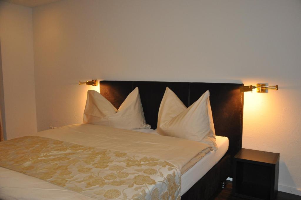 1 dormitorio con 1 cama con sábanas y almohadas blancas en Hotel Löwen, en Mellingen