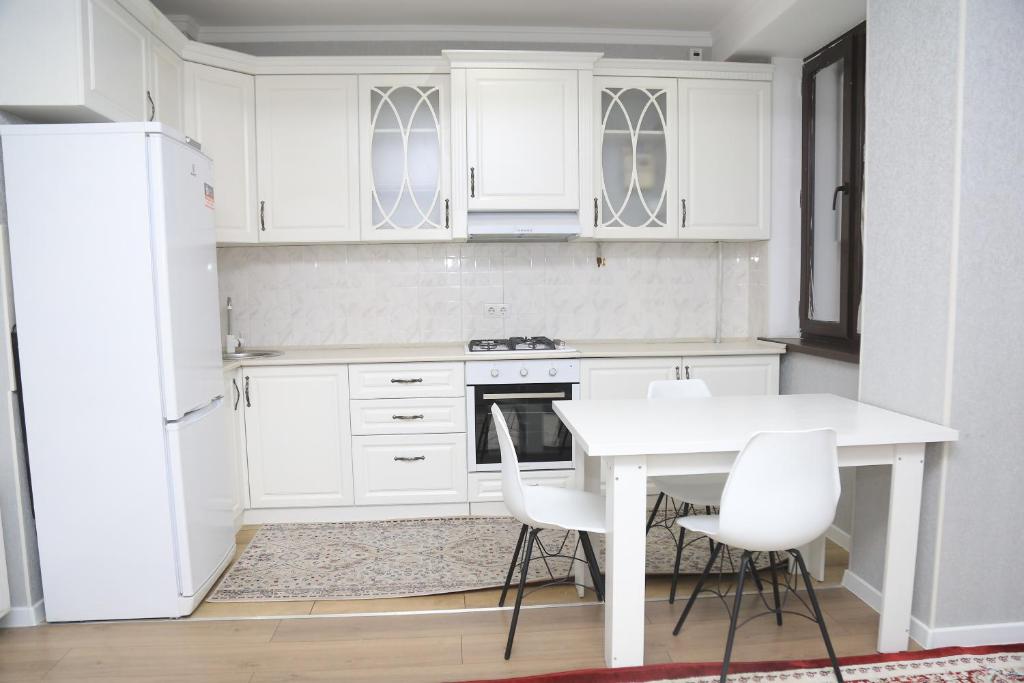 a kitchen with white cabinets and a white table and chairs at Апартаменты в центре Бишкека in Bishkek