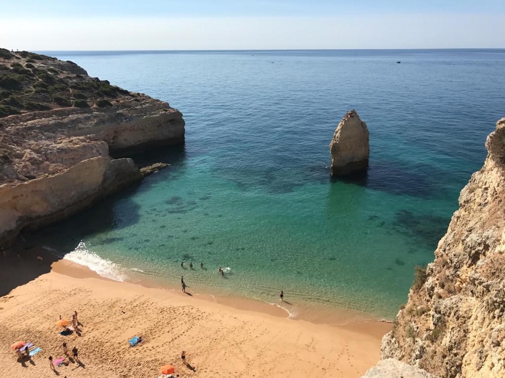 un grupo de personas en una playa cerca del océano en Casa Madrugada, en Carvoeiro