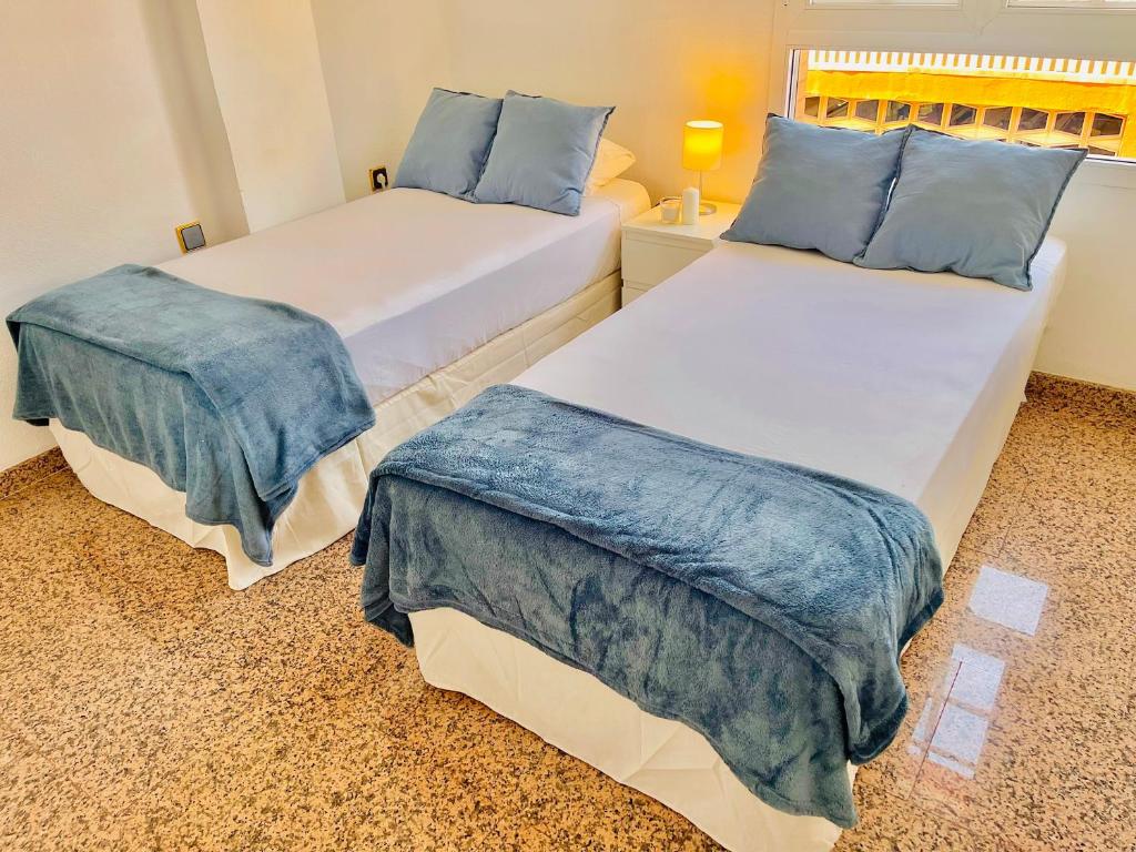 2 camas con almohadas azules en una habitación en Encantadora Habitación Privada cerca del mar en Málaga