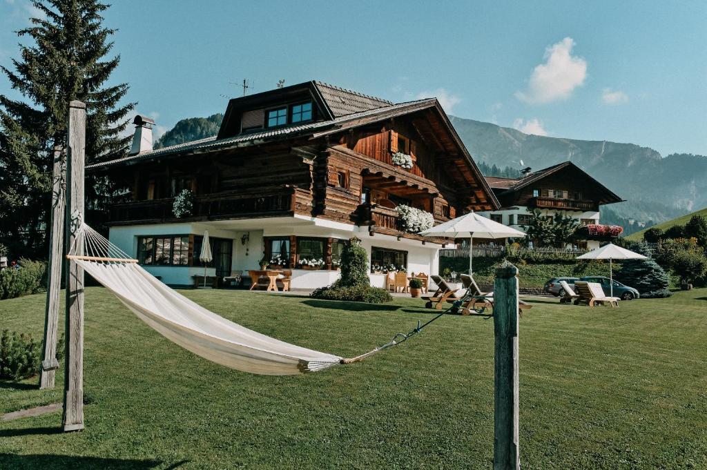 a log house with a hammock in front of it at Mountain Chalet Pra Ronch in Selva di Val Gardena