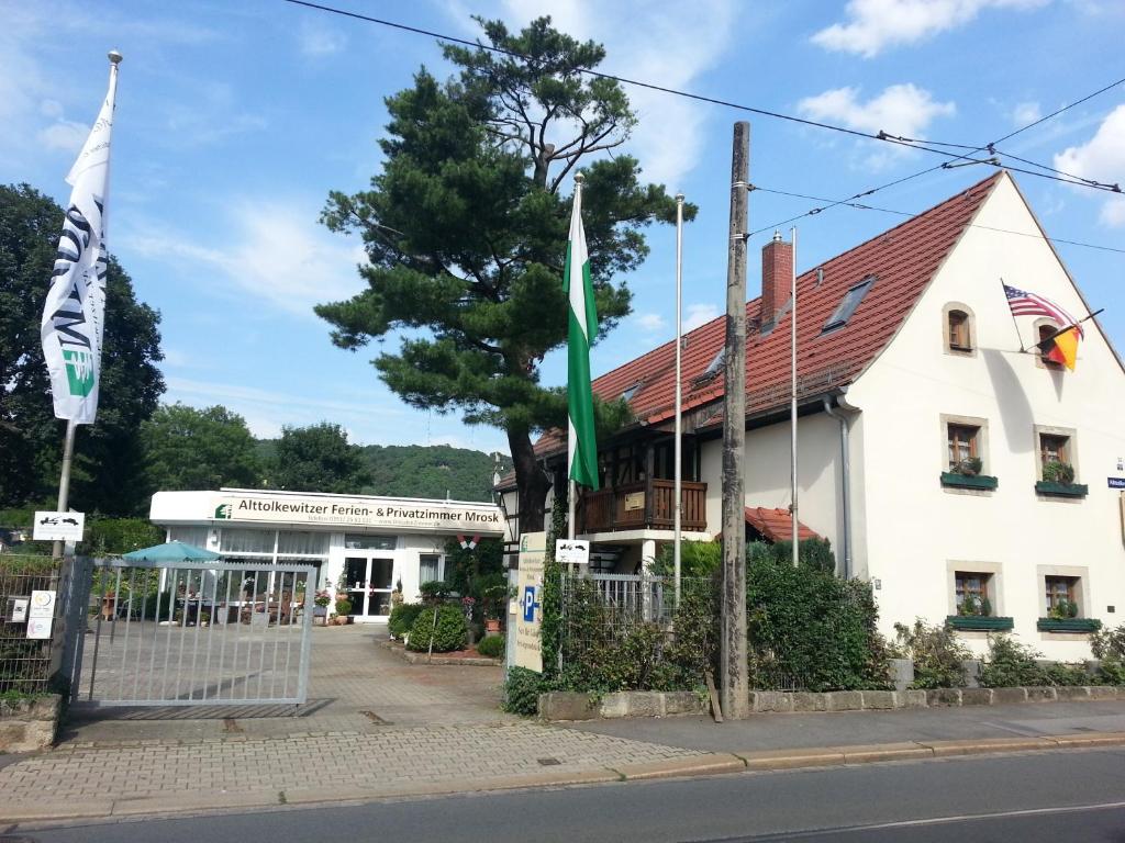 a white building with a flag in front of it at Alttolkewitzer Ferien- & Privatzimmer Mrosk Dresden in Dresden