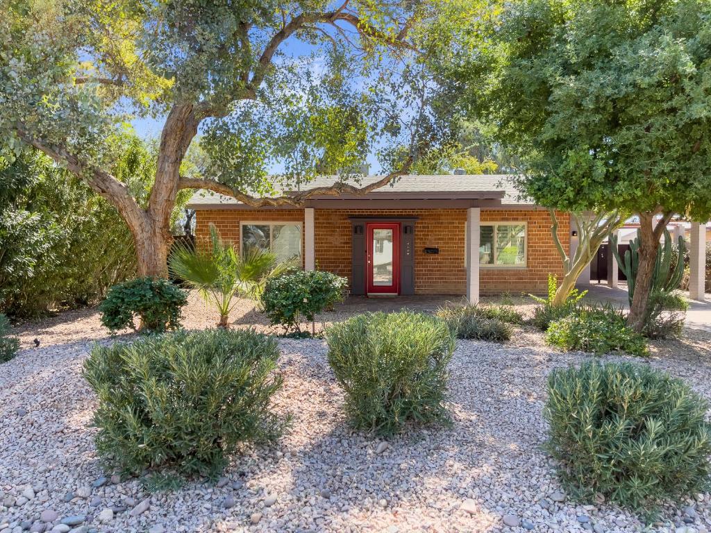 una casa con una puerta roja y árboles y arbustos en Casa Del Sol, en Phoenix