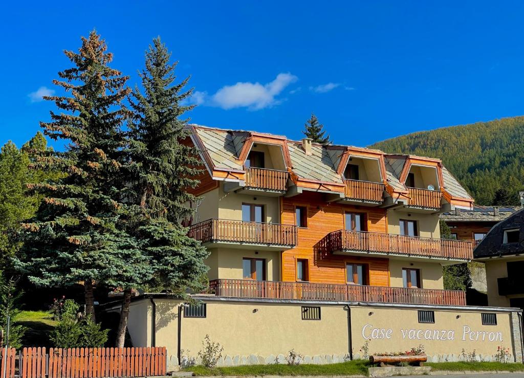 un gran edificio de apartamentos con una valla y un árbol en Case Vacanza Perron, en Sauze dʼOulx