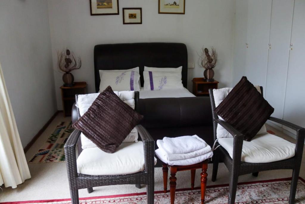 - une chambre avec un lit et deux chaises dans l'établissement Bougainvillea at Boskruin, à Johannesbourg