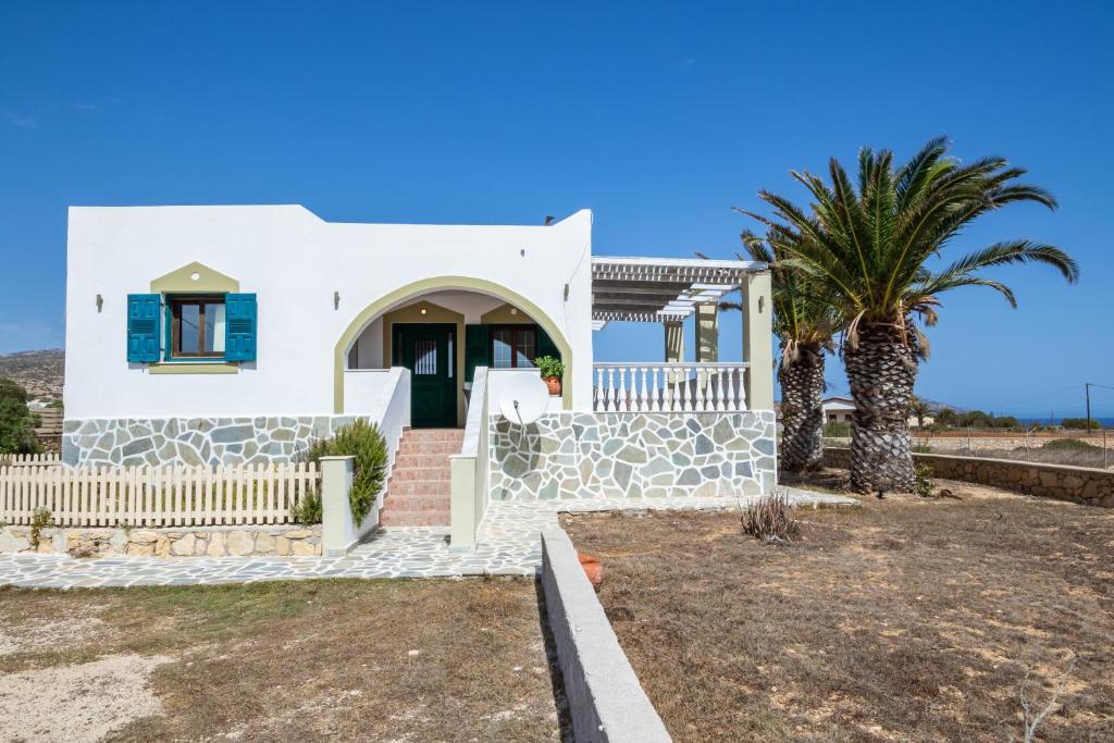a white house with a palm tree in front of it at Oceanviewvilla in Karpathos