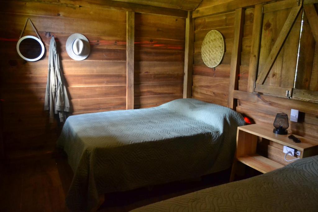 1 dormitorio con 1 cama en una habitación de madera en Pinar del Valle - Glamping en el Bosque - Propiedad Completa en Constanza, en Constanza