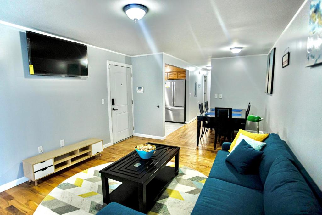 ein Wohnzimmer mit einem blauen Sofa und einem Tisch in der Unterkunft Urban Oasis Spacious 3BR 2BA Patio Near NYC EWR American Dream Mall in Newark