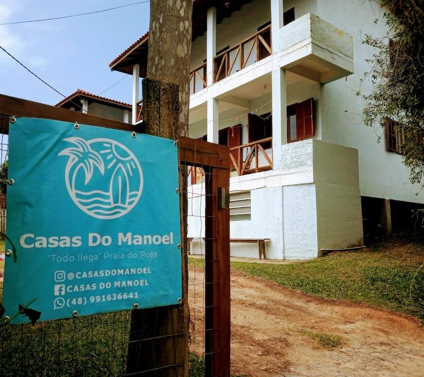 a sign on a fence in front of a building at Casas do Manoel in Praia do Rosa