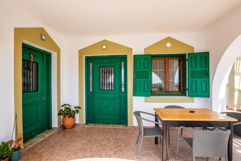 a dining room with green doors and a table at Oceanviewvilla in Karpathos
