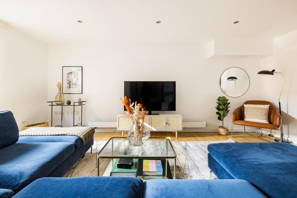 a living room with blue couches and a tv at The Clapham Dream - Captivating 3BDR with Garden & Parking in London