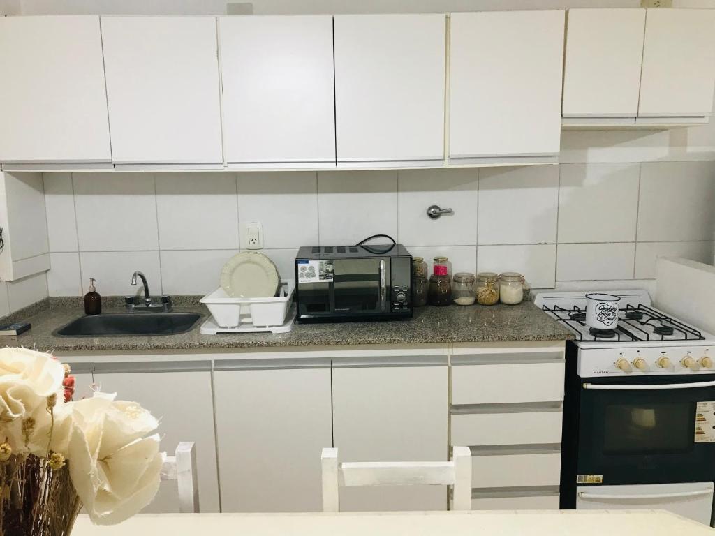 a kitchen with white cabinets and a sink and a microwave at Departamento luminoso y céntrico in Santiago del Estero