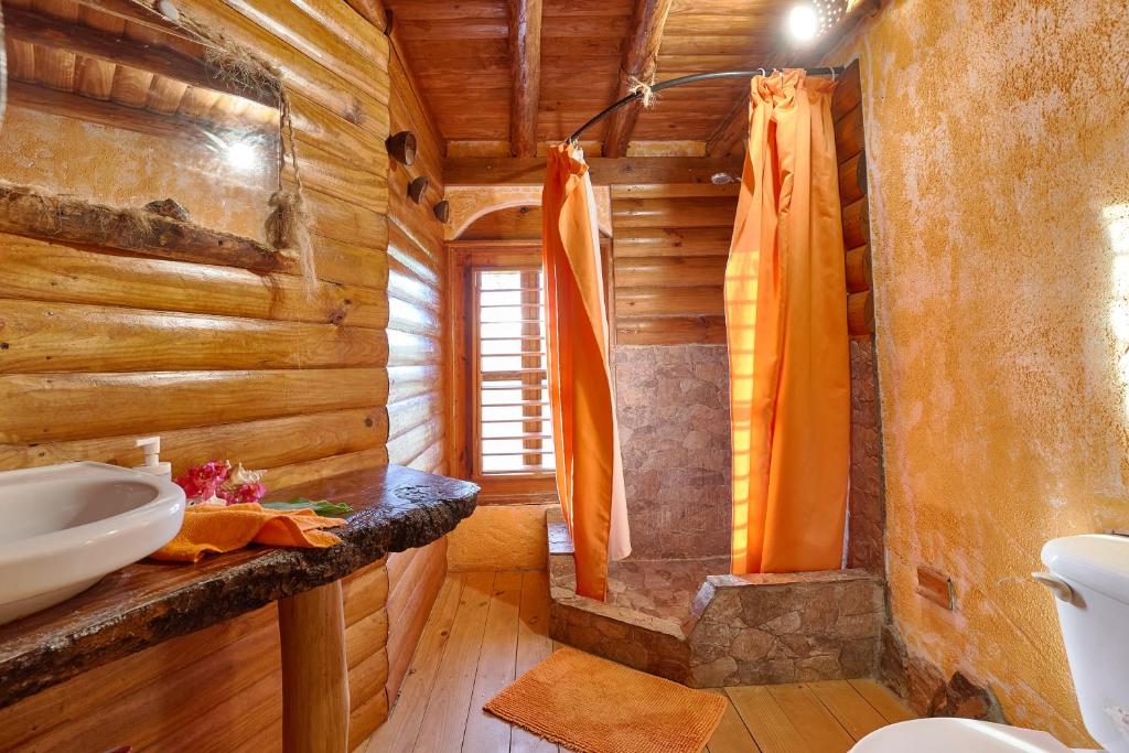 a bathroom in a log cabin with a sink at CHALET TROPICAL Hotel & Restaurant-Pizzeria in Las Galeras