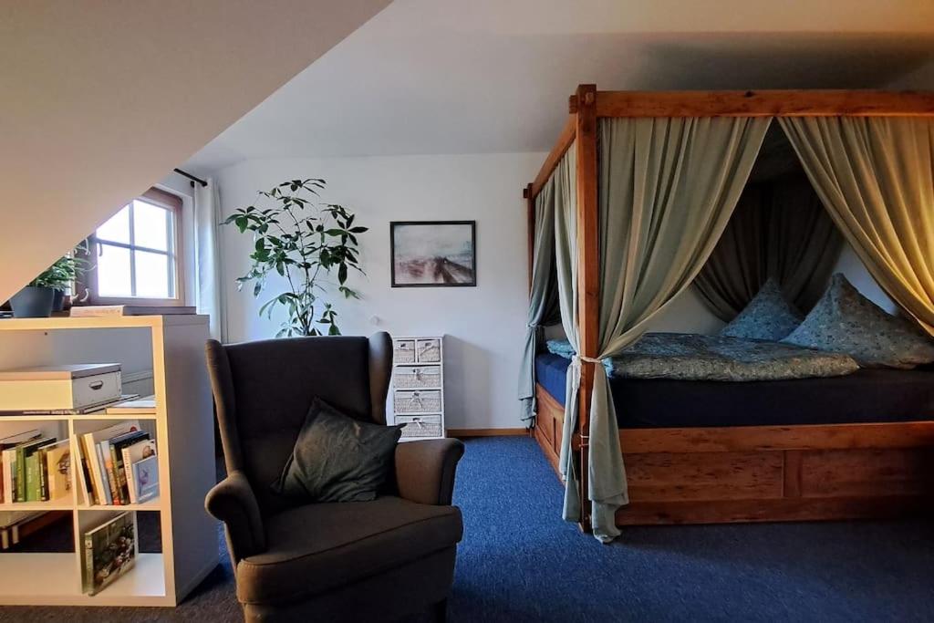 ein Schlafzimmer mit einem Himmelbett und einem Stuhl in der Unterkunft Gemütliche Waldrandlage in Badenweiler Sehringen Ferienwohnung in Badenweiler